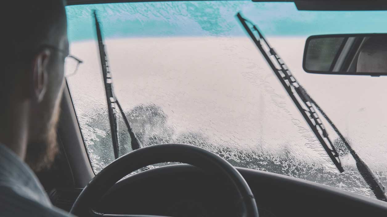 Homme dans sa voiture qui se pose des questions à propos de son pare brise